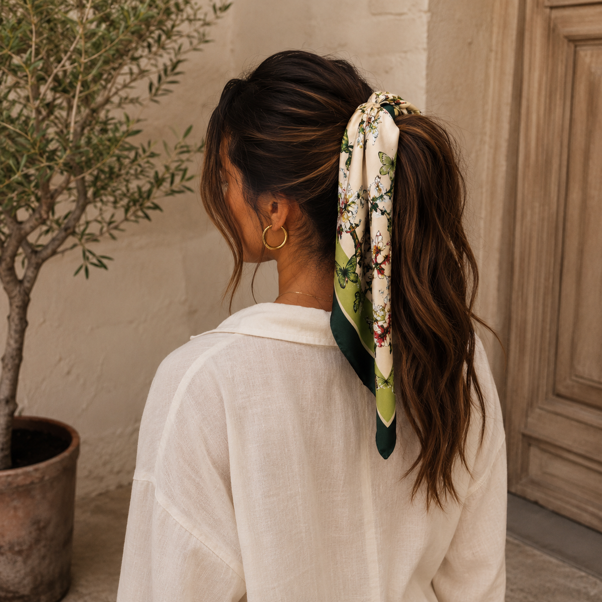 Pañuelo de seda anudado alrededor de una coleta, con los extremos cayendo sobre el cabello.